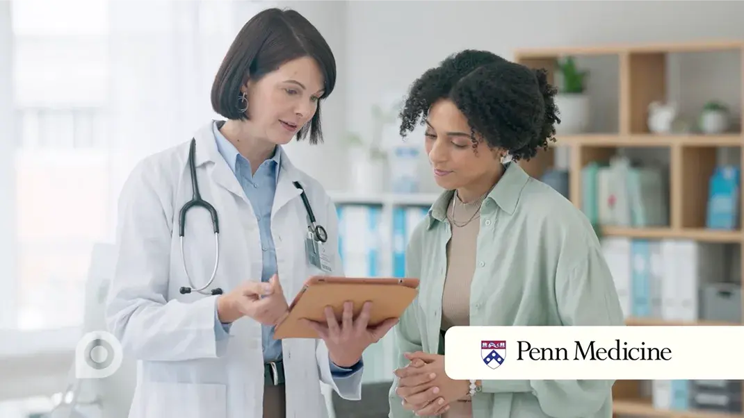 Doctor and her patient reviewing charts with Penn Medicine Logo